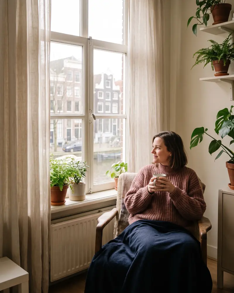 Vrouw met een kop thee bij het raam in een rustig appartement